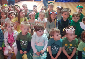 dzieci ubrane w zielone, wiosenne stroje obserwują prezentację o wiośnie na tablicy multimedialnej